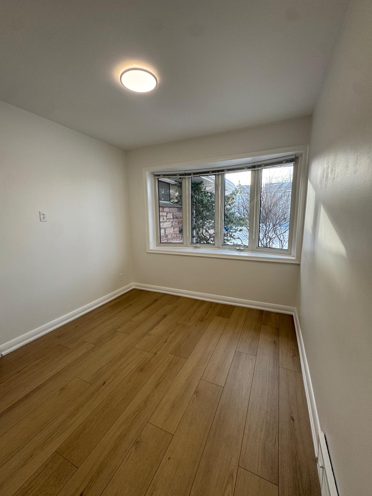 Bedroom with natural oak hardwood floors and bay window